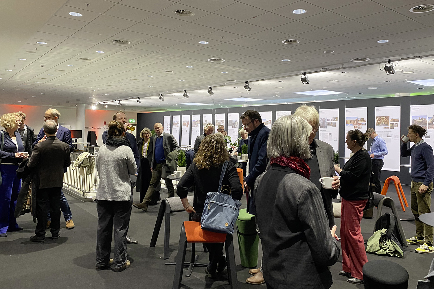 Eine große Menschengruppe auf einer Konferenz, im Hintergrund Stelen